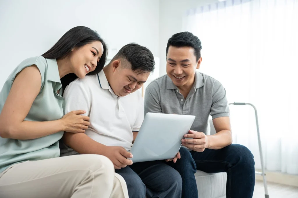 Disabled man sitting on couch with parents holding laptop