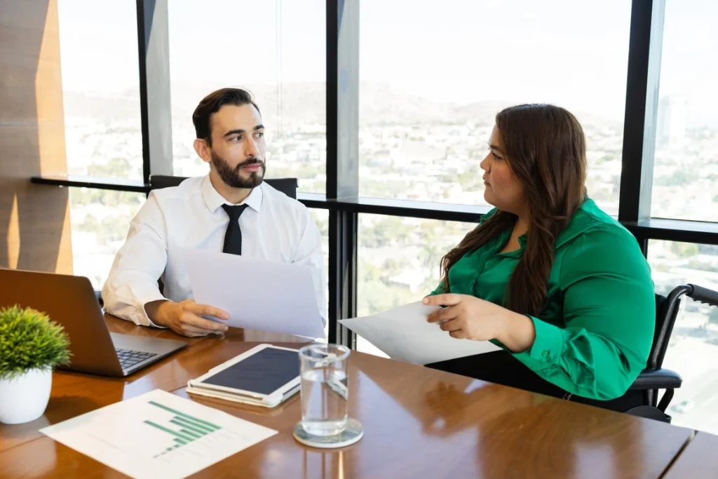 Disabled woman in wheelchair sitting in office talking with Support Coordinator