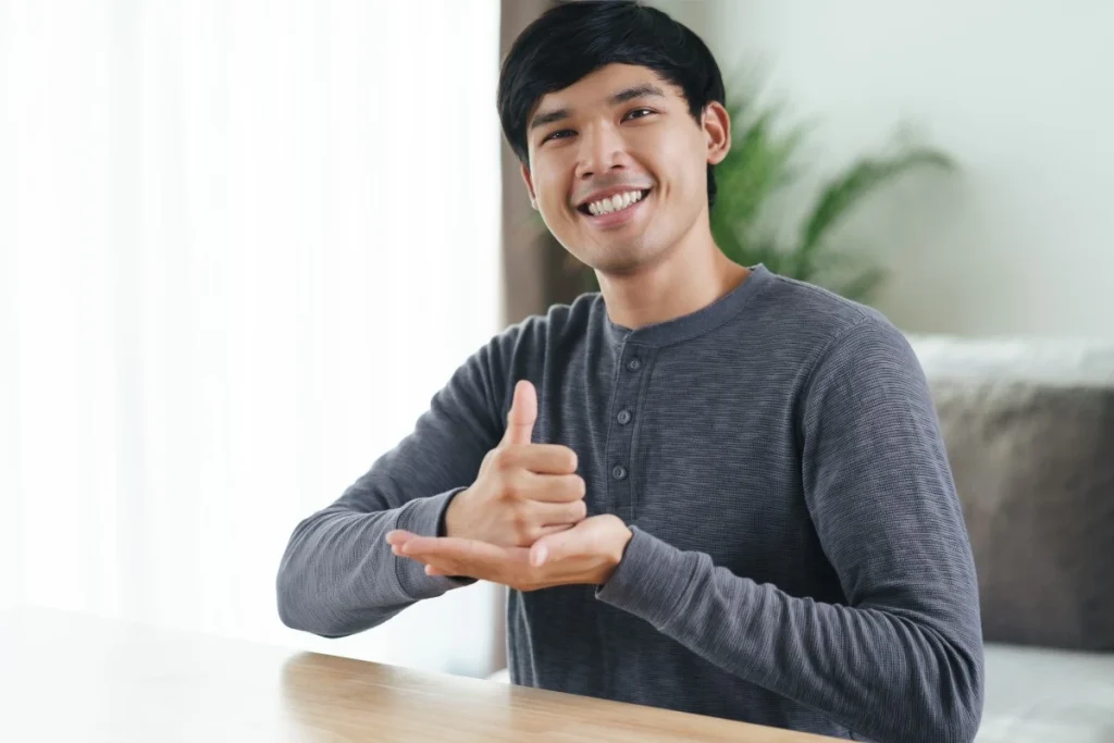 Disabled man smiling at camera and using sign language