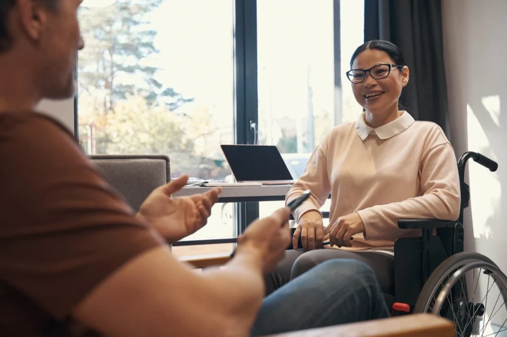 Happy disabled woman in wheelchair smiling with support worker