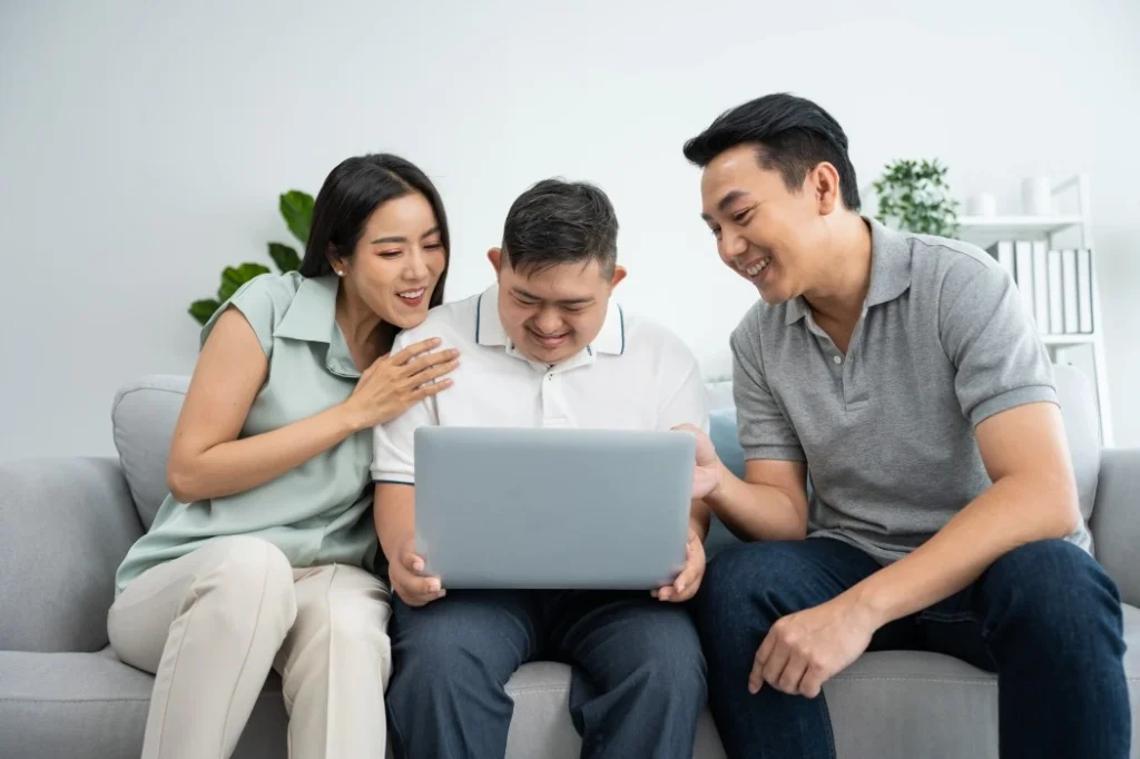 Disabled man using laptop to contact H3 care with parents